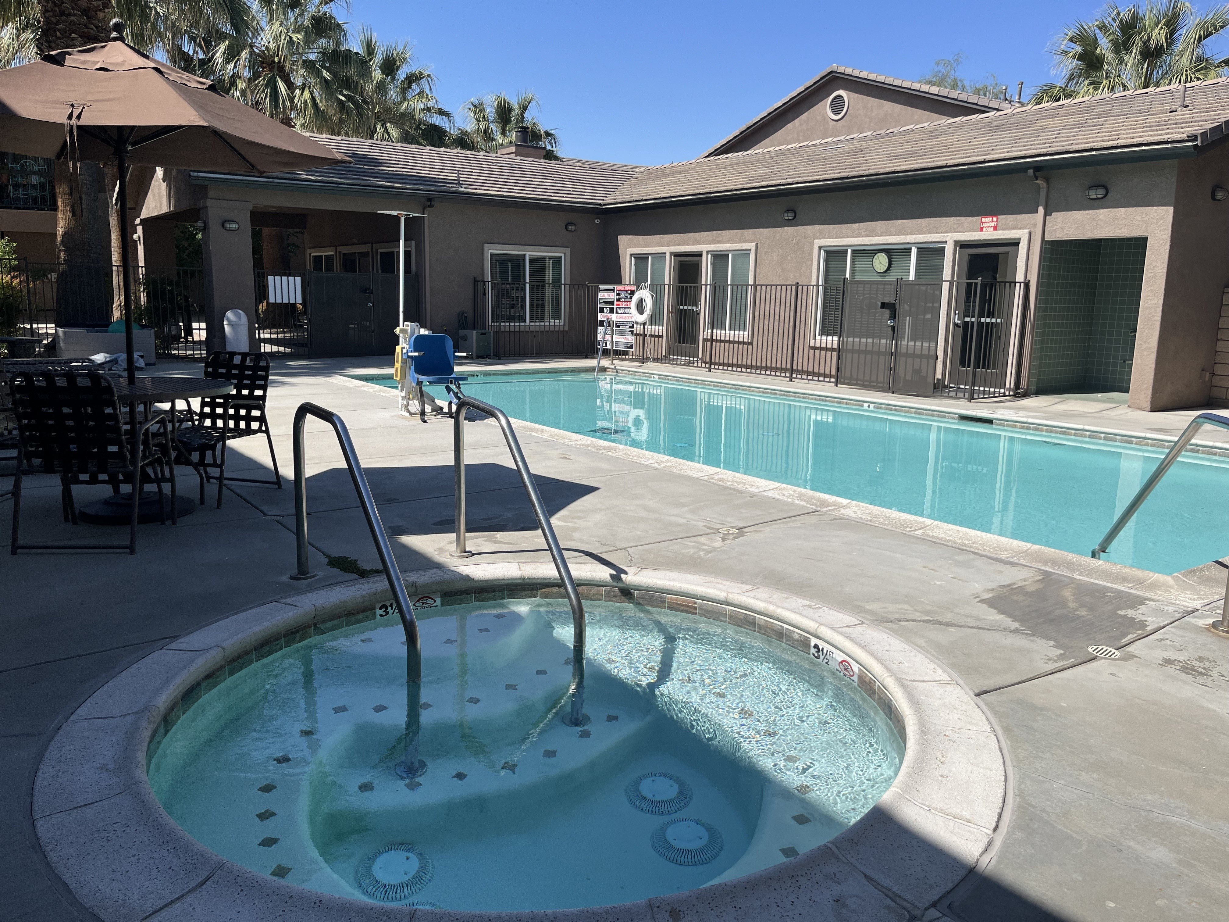 a swimming pool in the courtyard of a house with a pool and patio with chairs