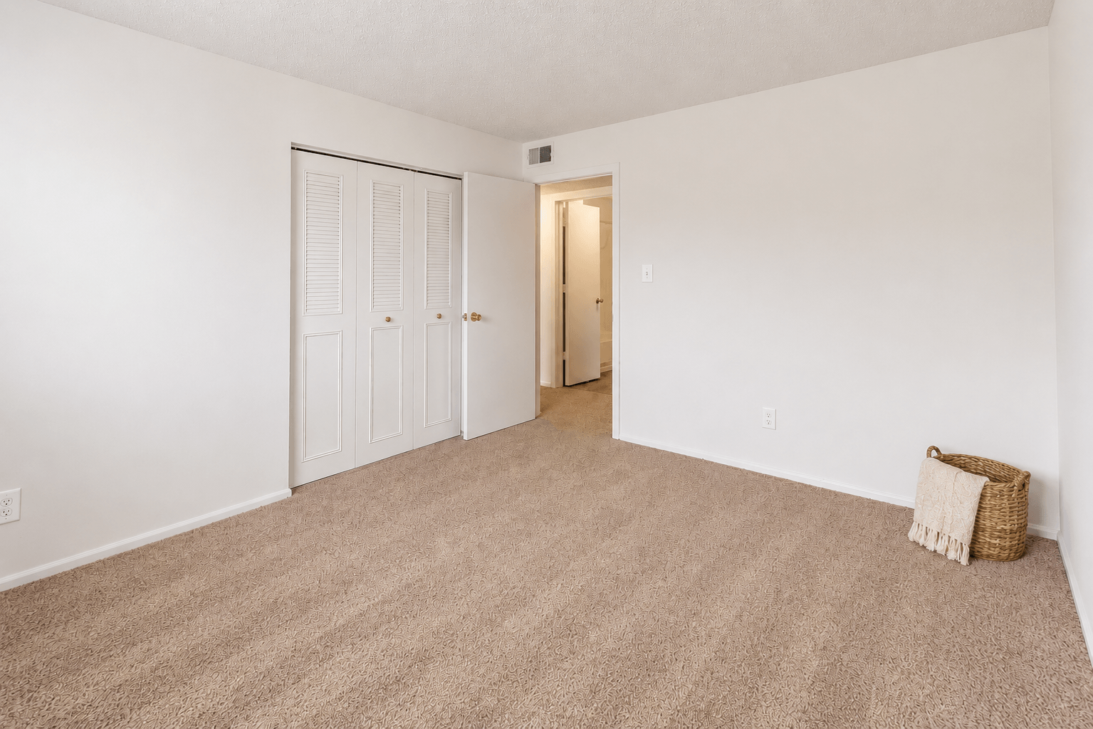 A room with a carpeted floor and a door.