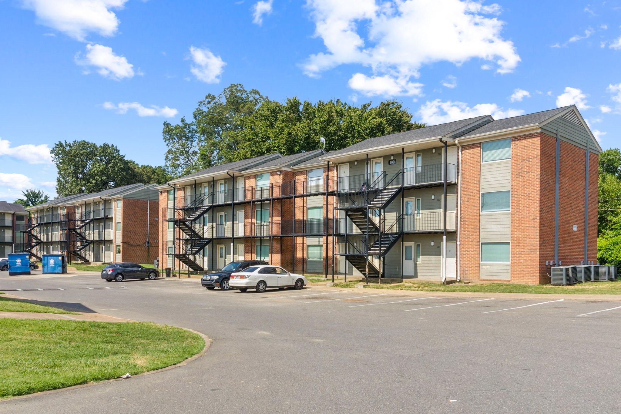 A large apartment complex with a parking lot in front.