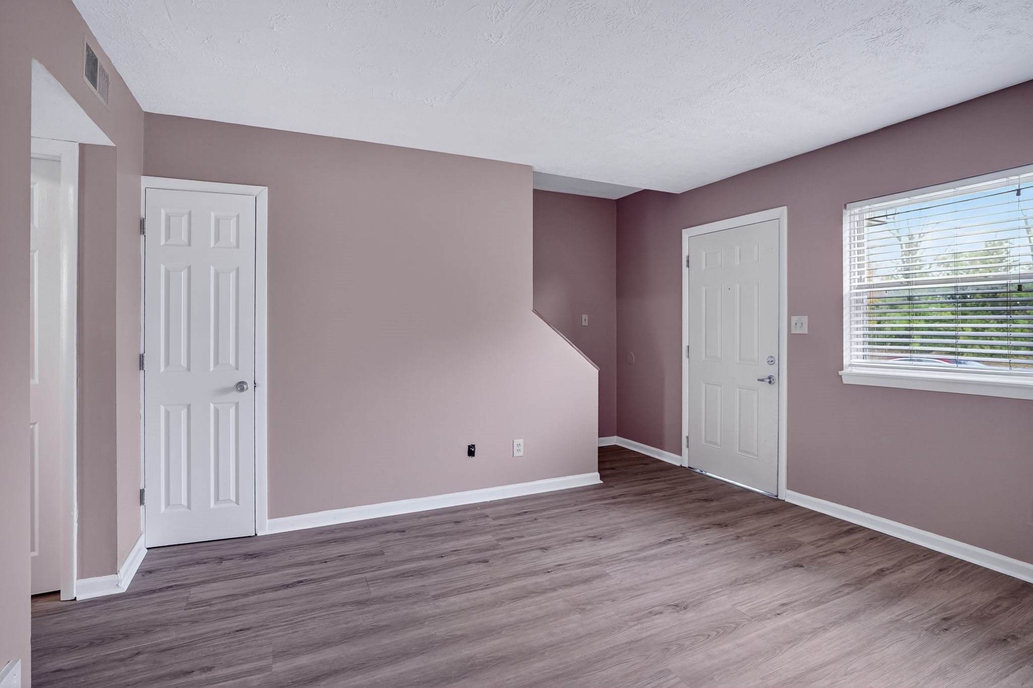 A room with a window and two doors.