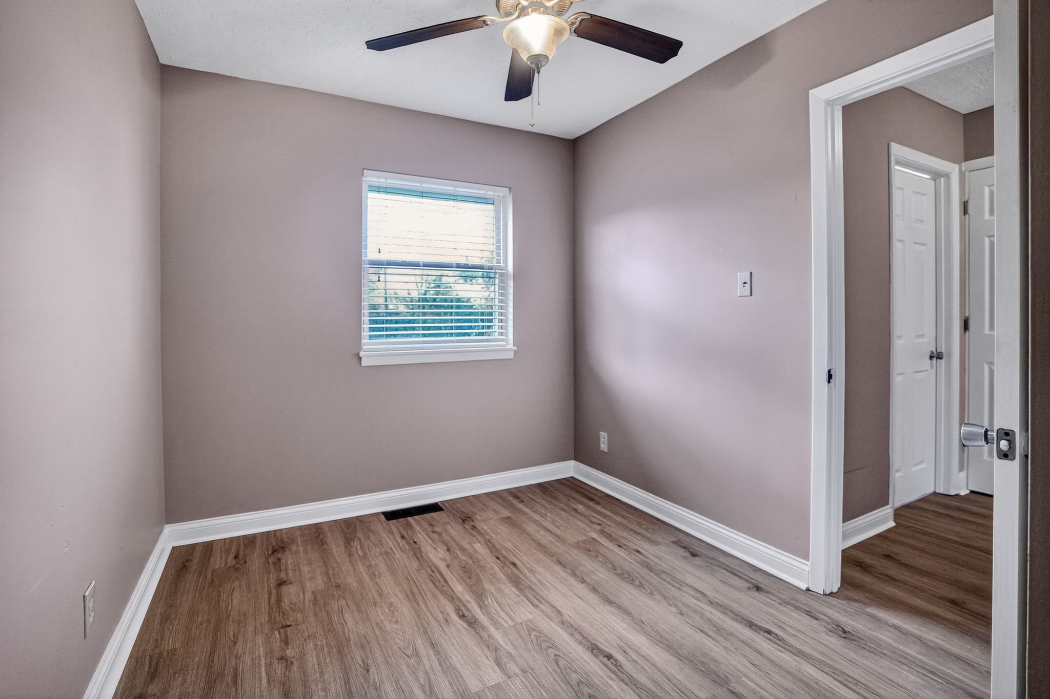 A room with a ceiling fan and a window with blinds.