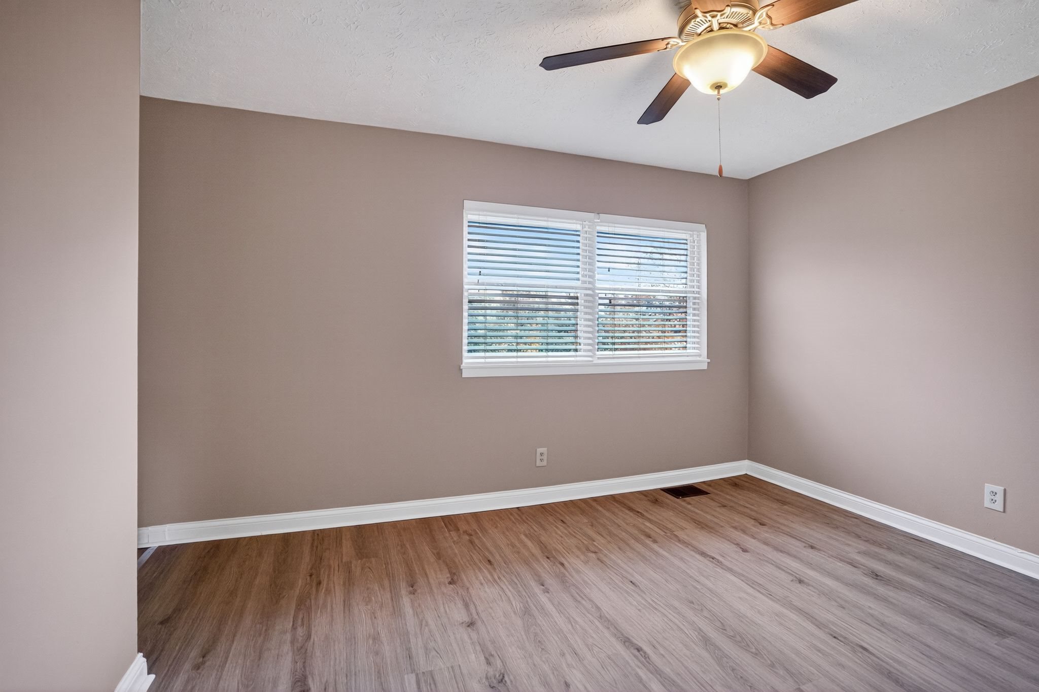 A room with a ceiling fan and a window with blinds.