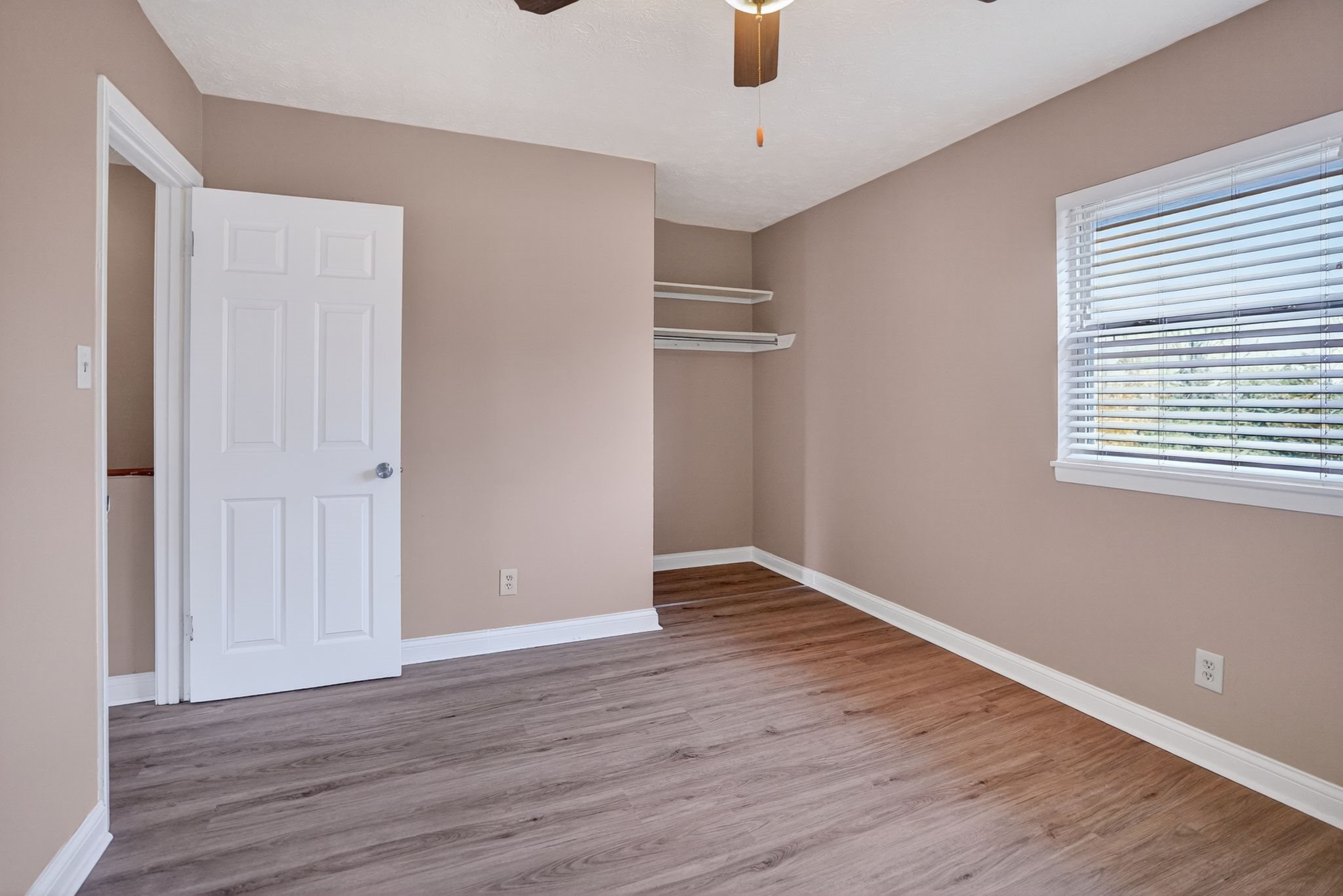 A room with a white door and a window with blinds.