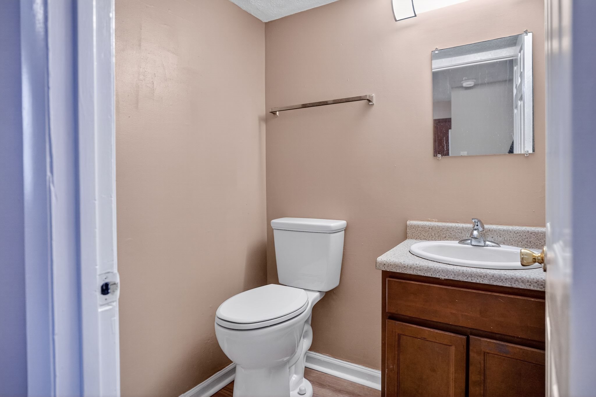 A bathroom with a toilet, sink, and mirror.
