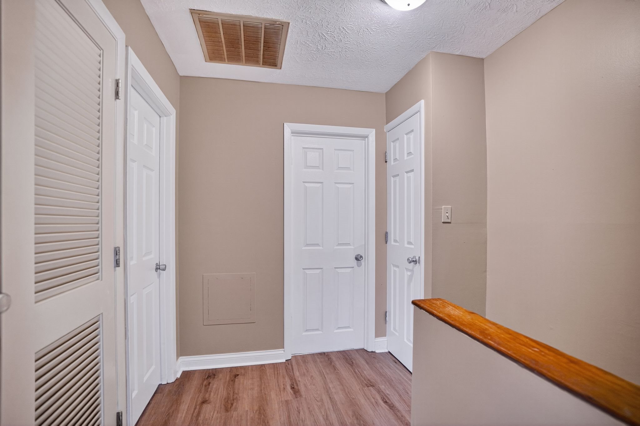 A hallway with white doors and a wooden bench.
