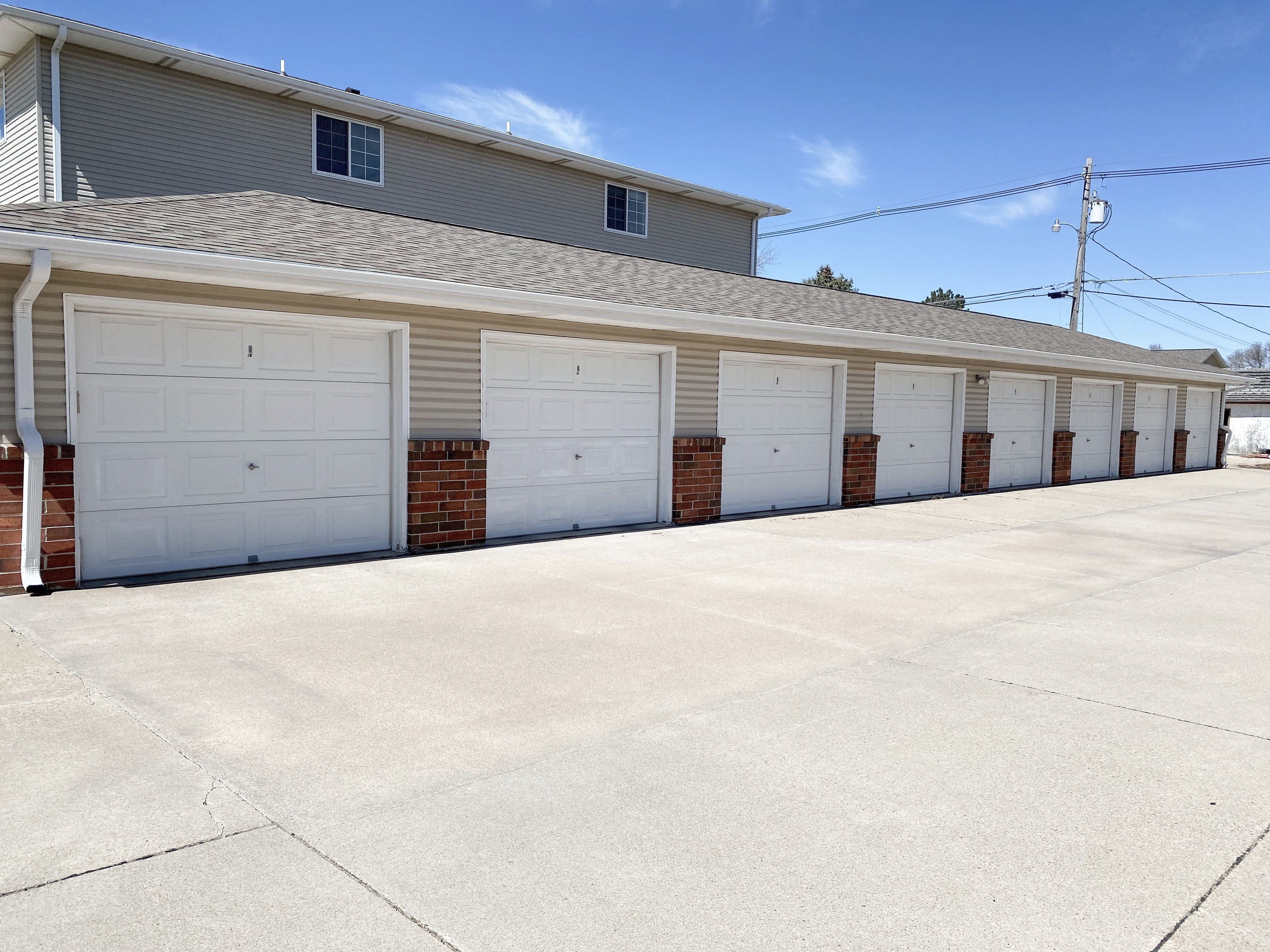 a row of white garage doors in front of a house