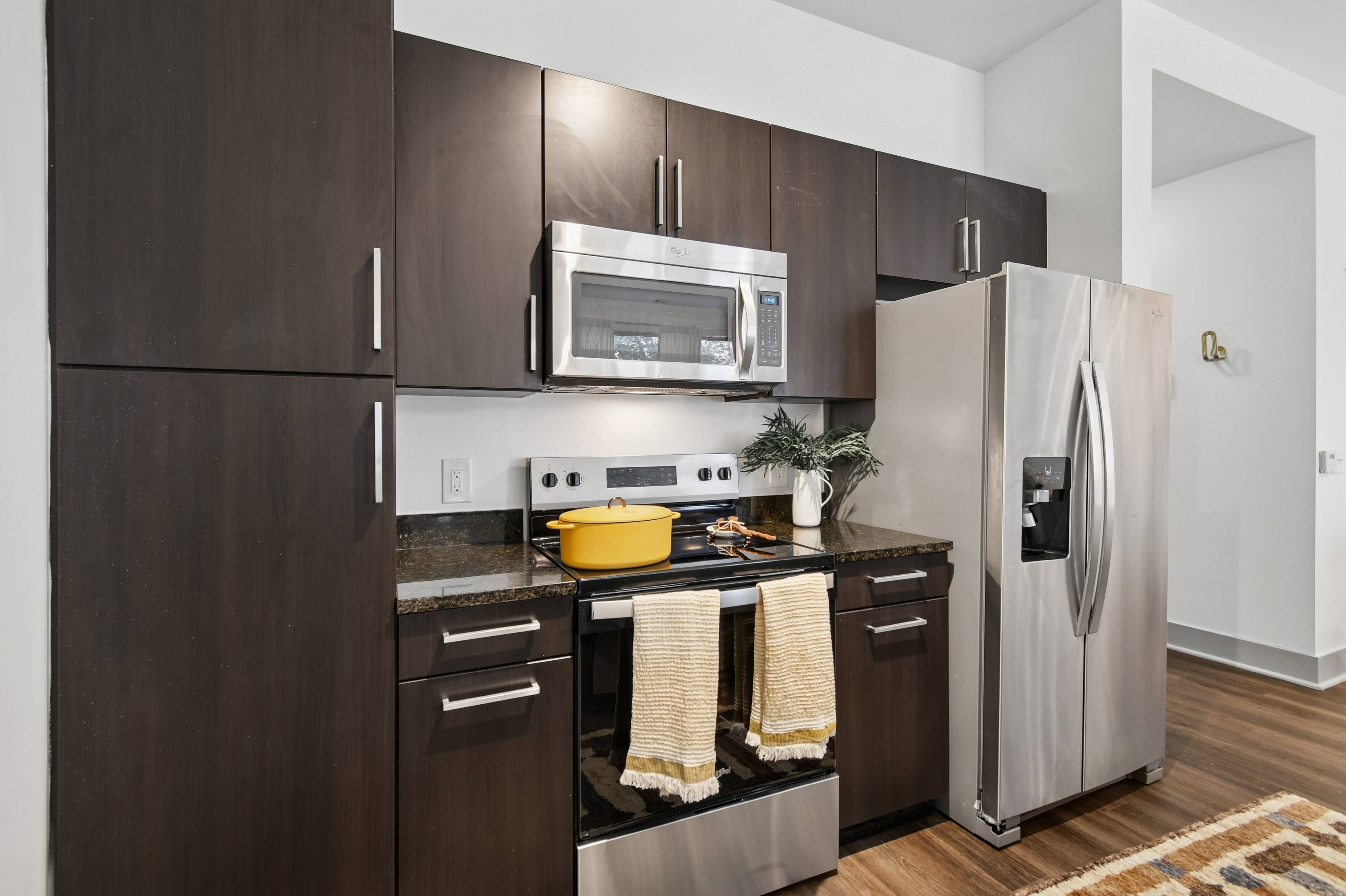 A modern kitchen with dark wood cabinets and stainless steel appliances.