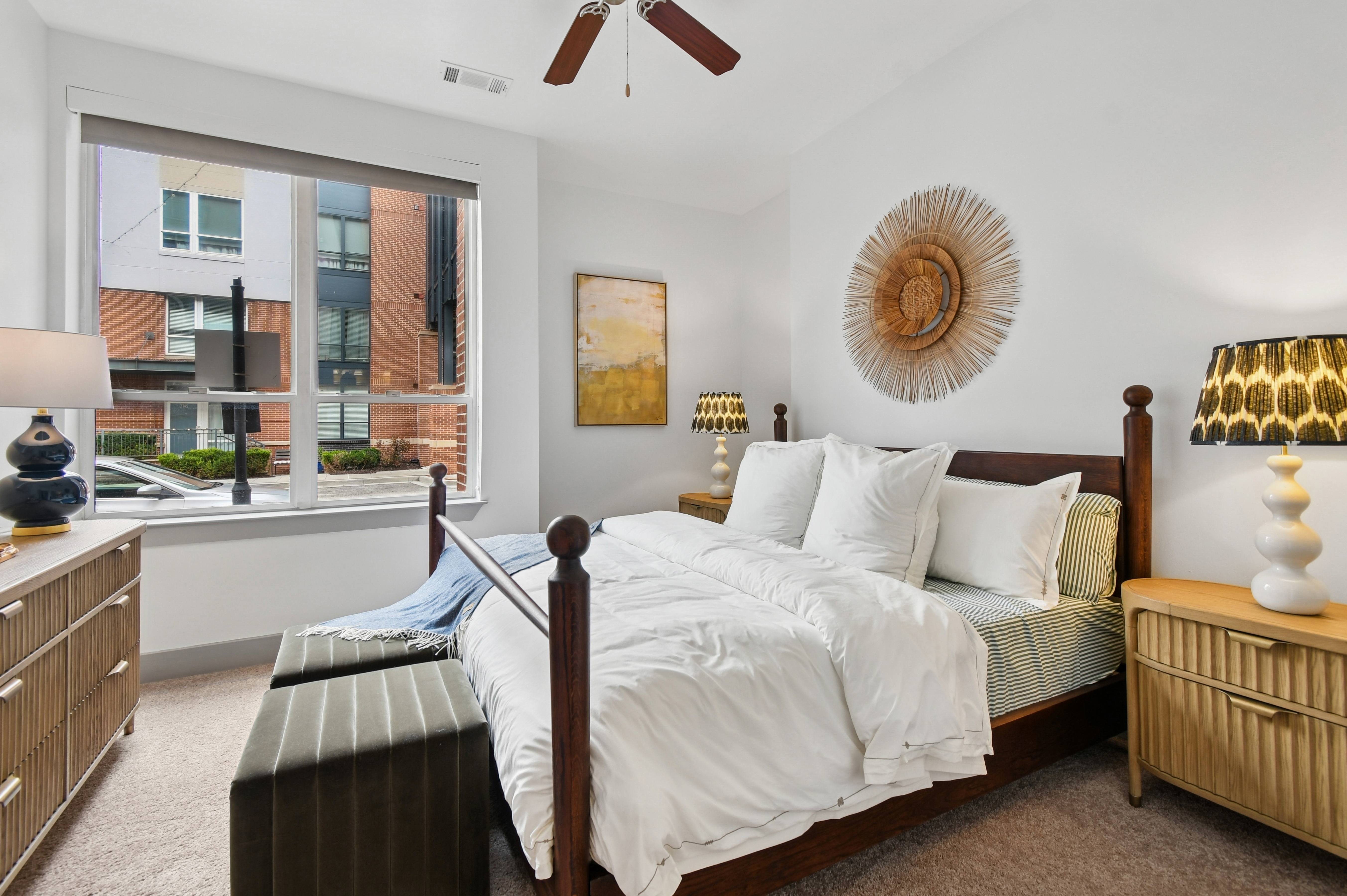 A bedroom with a large bed and a view of a city street outside the window.