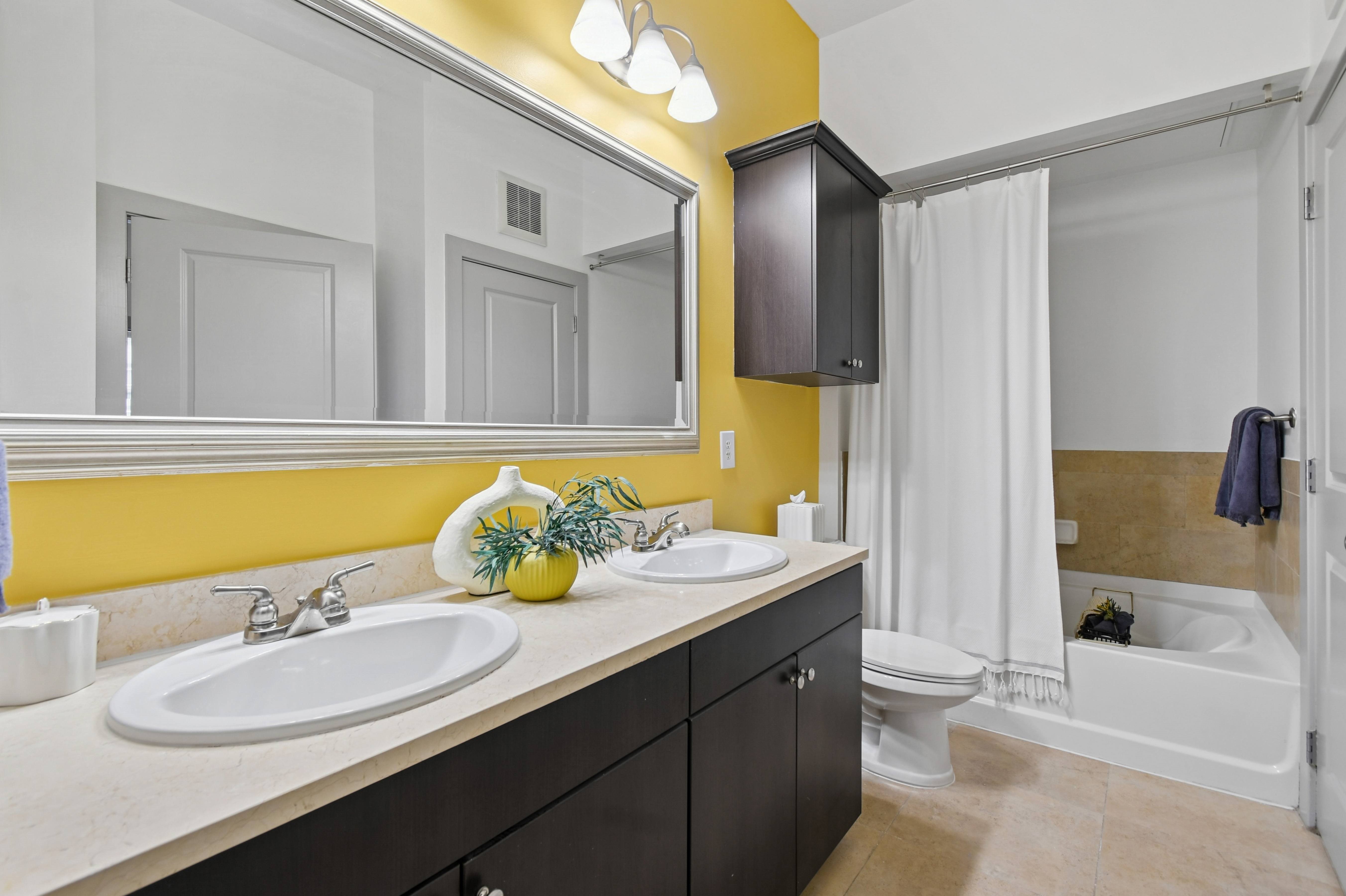 A bathroom with a white sink and a yellow wall.