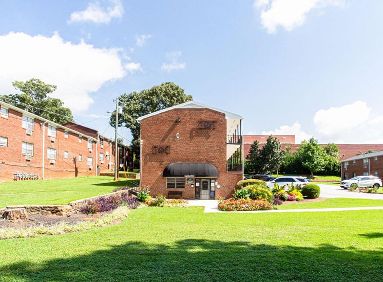 a brick building with a black awning in the middle of a grassy area