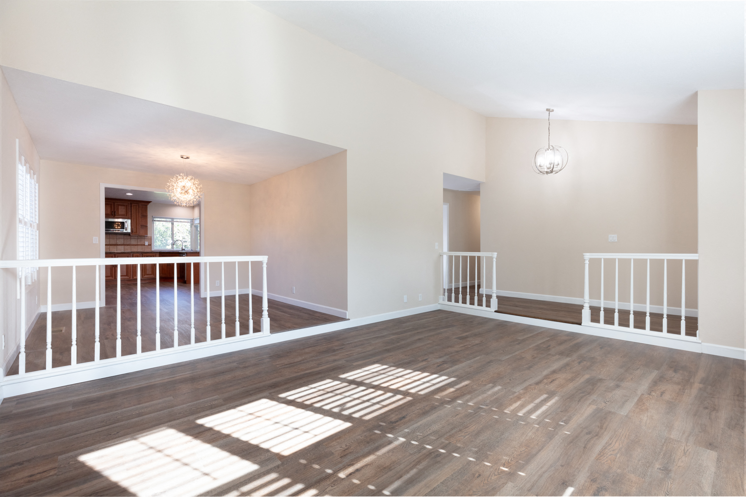 an empty living room with stairs and a kitchen