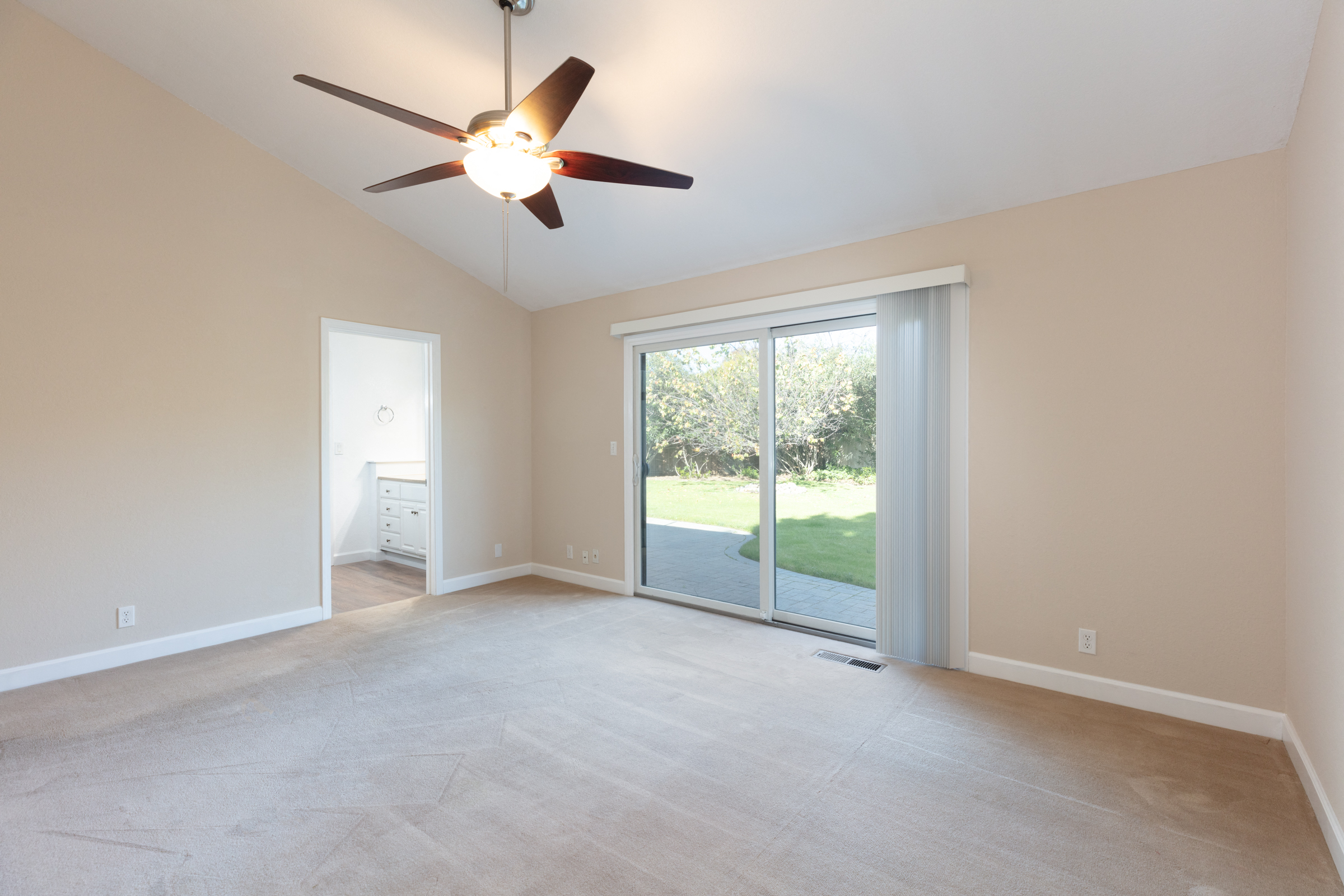 an empty living room with a ceiling fan and sliding glass doors
