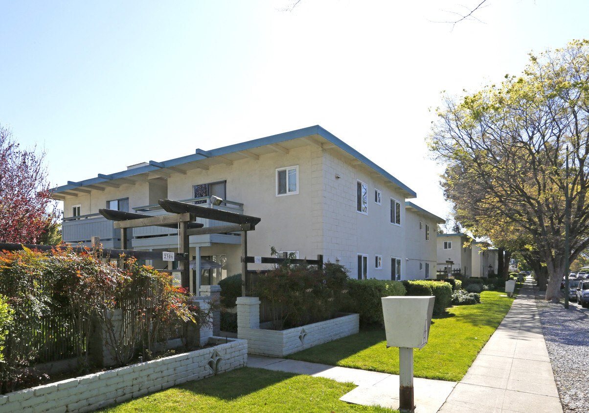 A white house with a blue roof and a mailbox on the sidewalk.