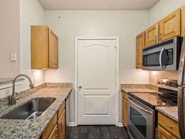 Kitchens with Raised Panel Cabinetry, Granite Like Countertops, Black Appliance Packages and Undermount Lighting at Cambridge Square Apartments, Overland Park, KS 66211