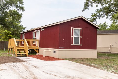 Red mobile home exterior with large driveway at Maple Grove, Nebraska
