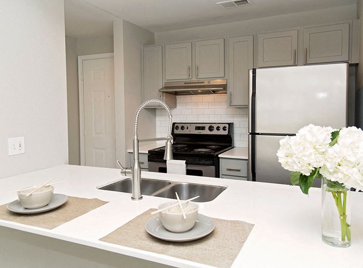 Model kitchen with place settings and floral arrangement on counter