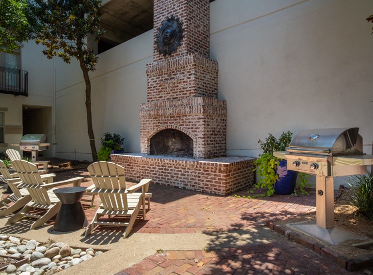 Outdoor chairs in front of BBQ and brick fireplace