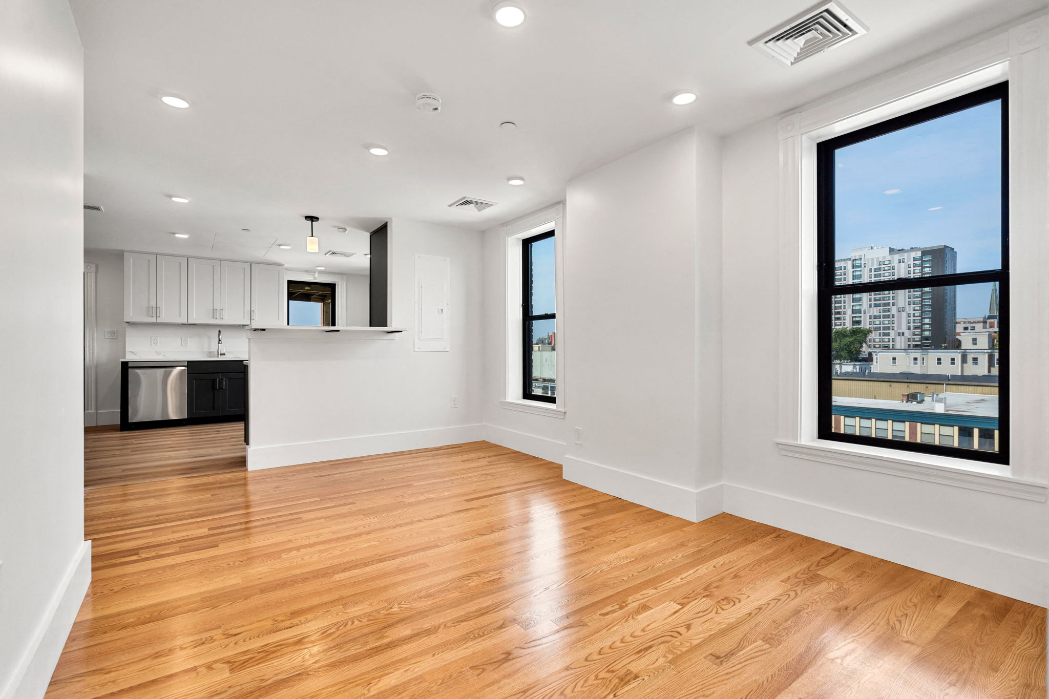 440-7 an empty living room with a large window and a kitchen