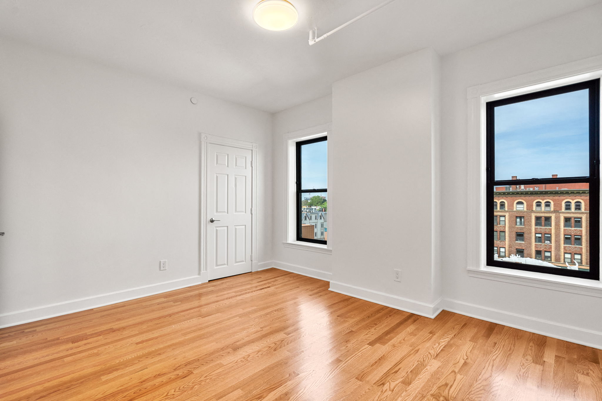 440-7 an empty living room with wood floors and two windows