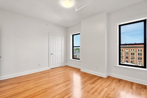 440-7 an empty living room with wood floors and two windows
