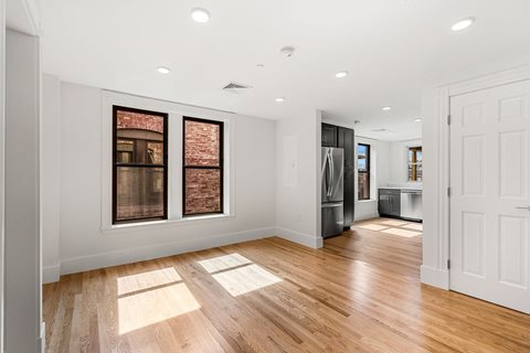 a renovated living room with wood floors and a kitchen