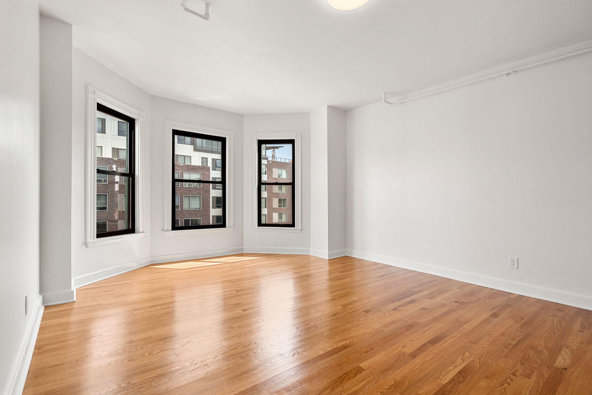 an empty living room with wood floors and windows