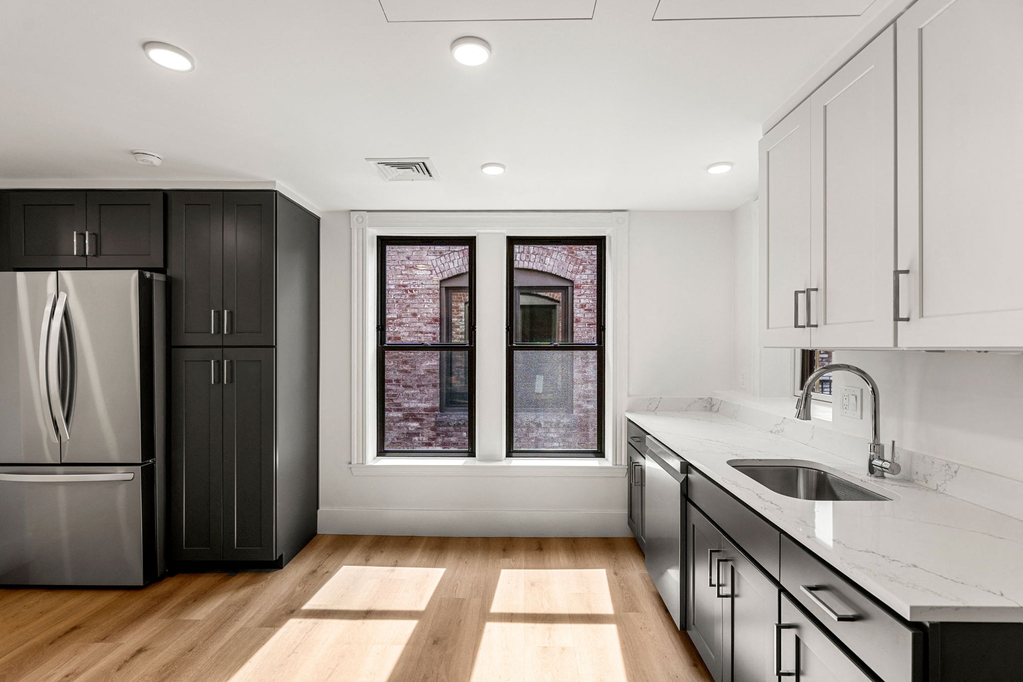a kitchen with black and white cabinets and a window
