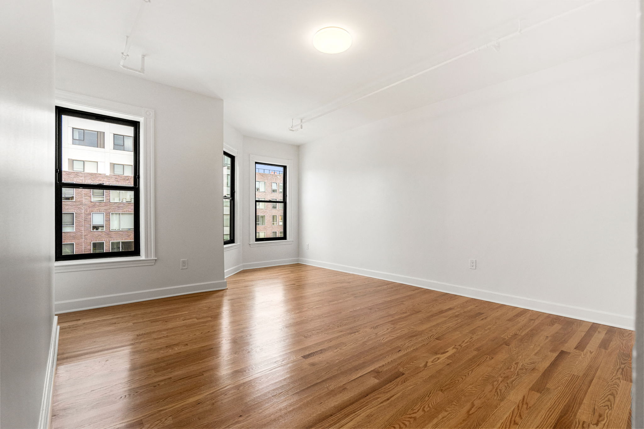 an empty living room with wood floors and a large window