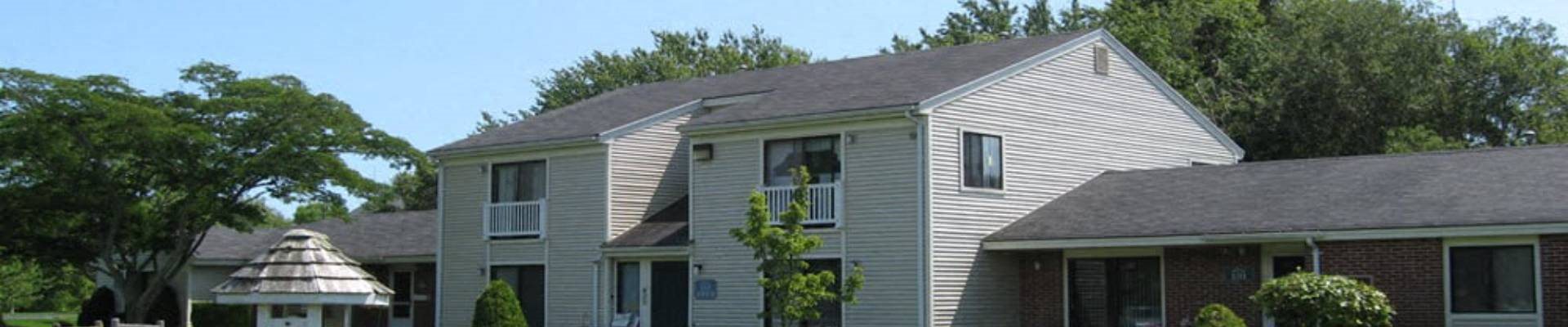 a white house with a gray roof and a tree