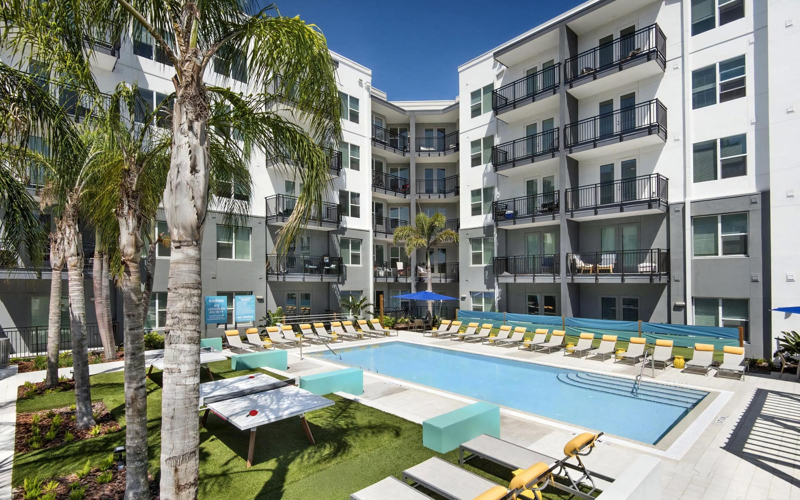 Courtyard Pool Surrounded by Lounge Chairs, Ping Pong Tables, and Palm Trees