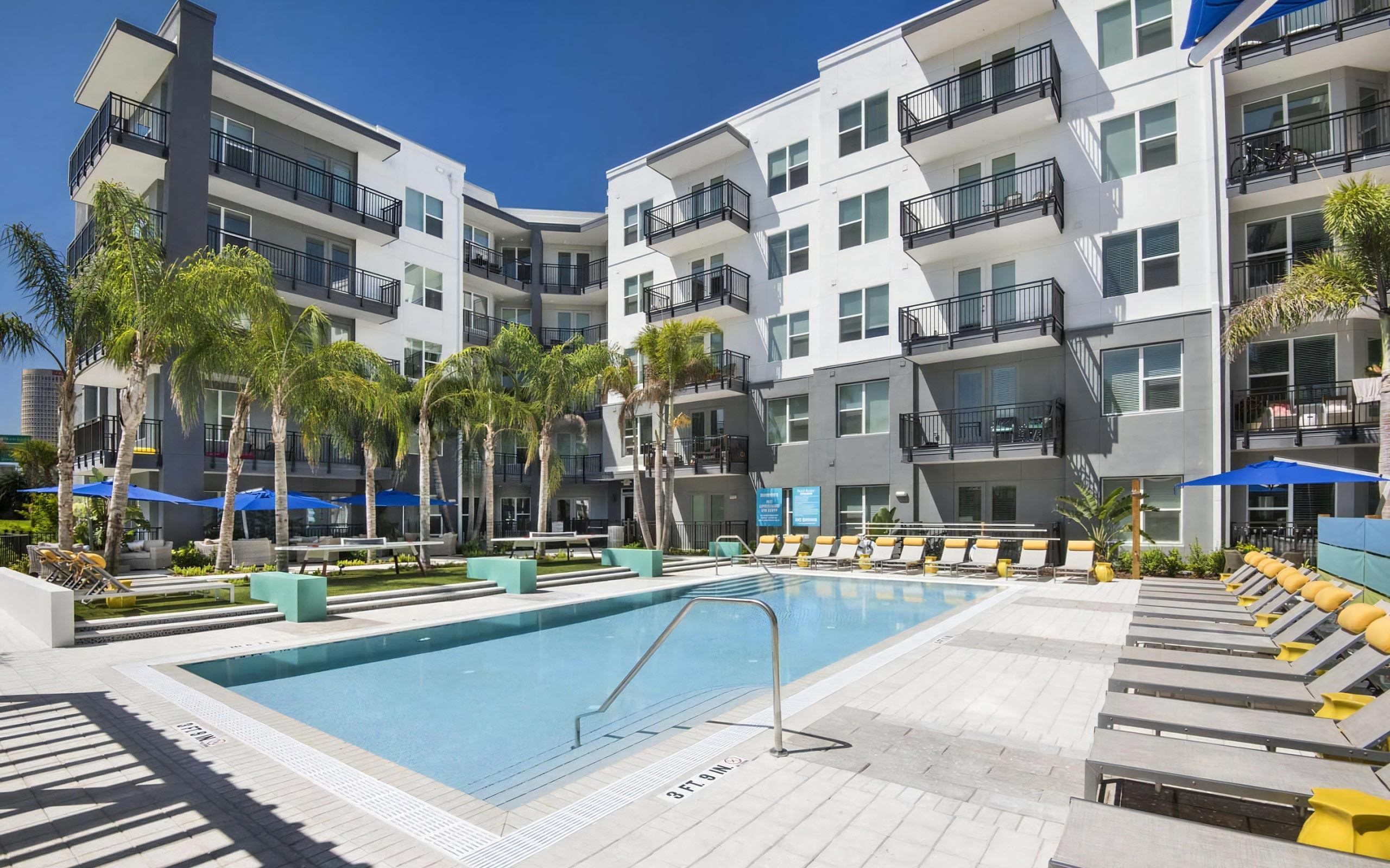 Resort-Style Pool Surrounded by Palm Trees, Sun Loungers, and Courtyard Views