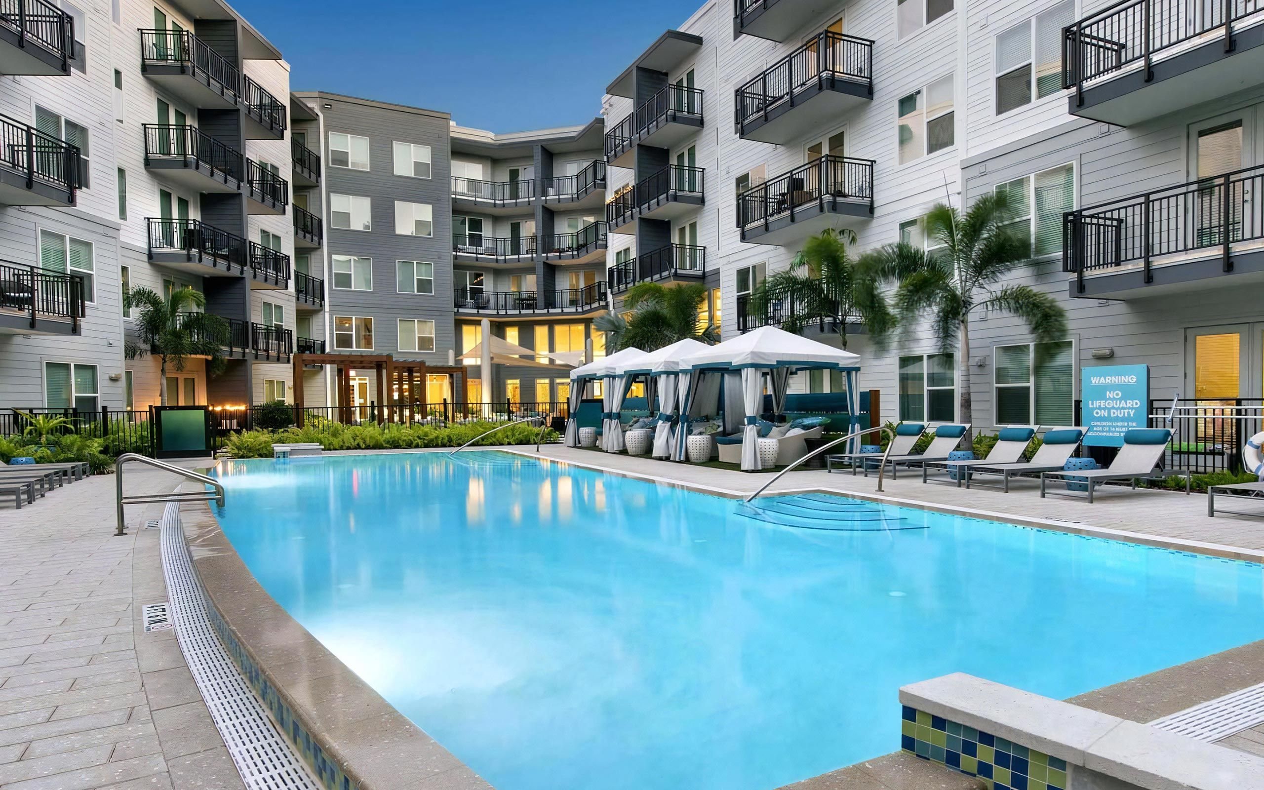 Evening Poolside Setting with Resort-Style Cabanas and Cushioned Loungers
