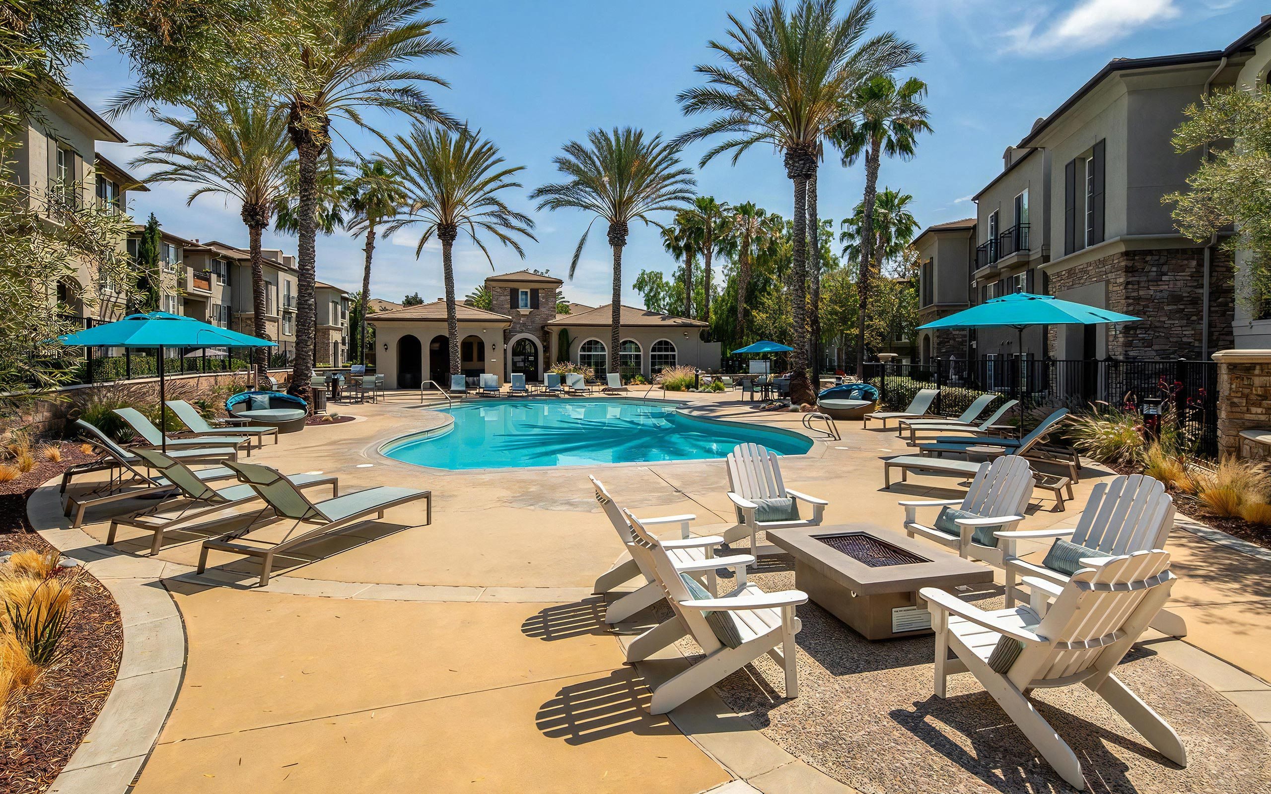 Expansive Pool Deck Featuring Firepit, Lounge Chairs, and Palm Trees