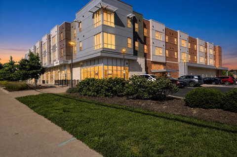 A modern apartment building with a parking lot in front.