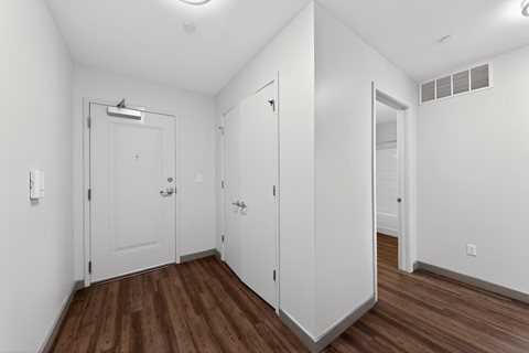 A white room with wood floors and a door with a handle.