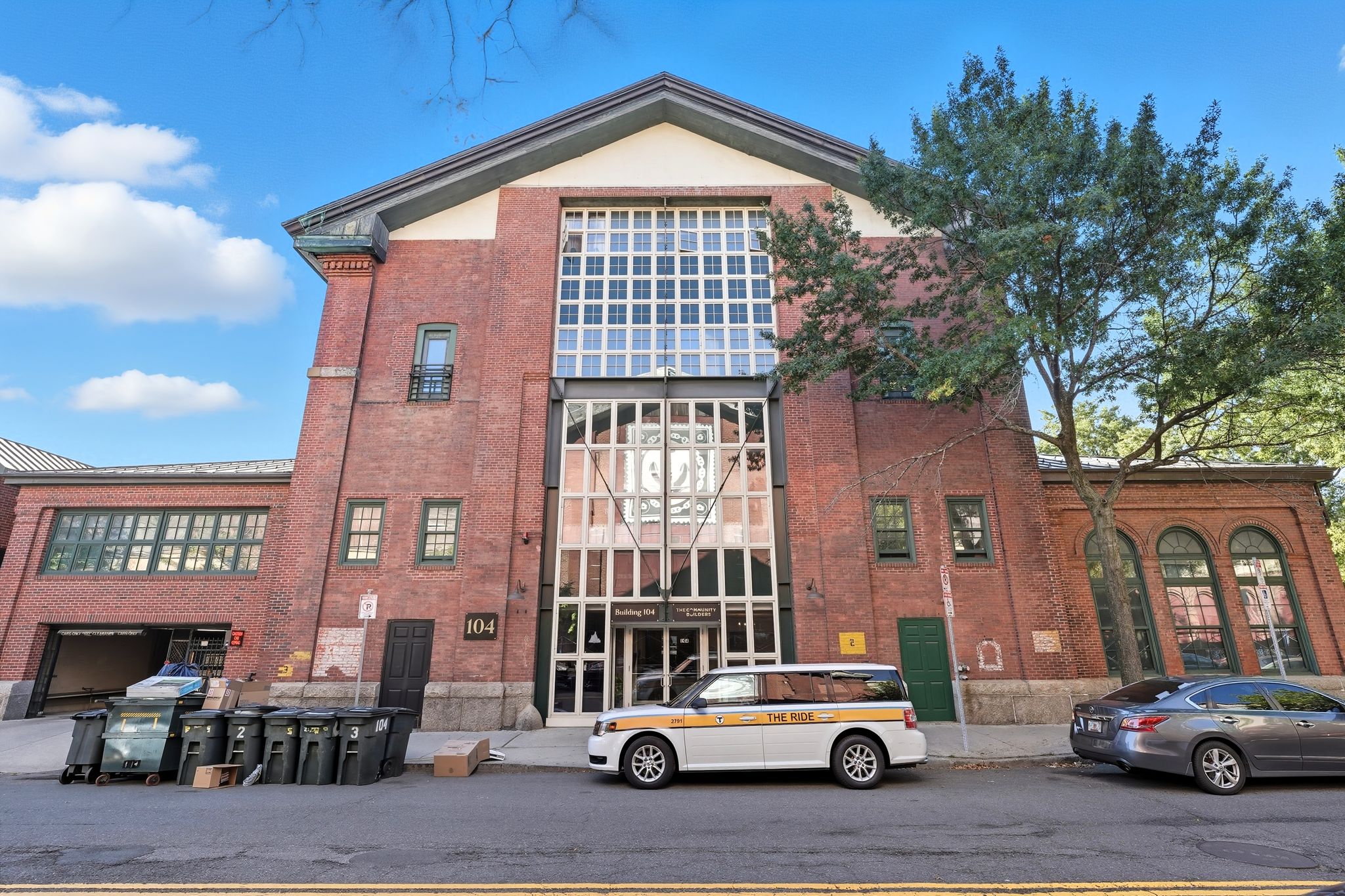 A white car is parked in front of a red brick building.