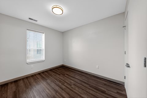 A room with a window and a wooden floor.