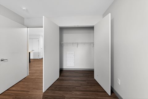 A white hallway with a door on the left and a closet on the right.