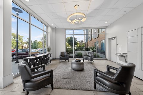 A modern waiting room with black leather chairs and a large window.