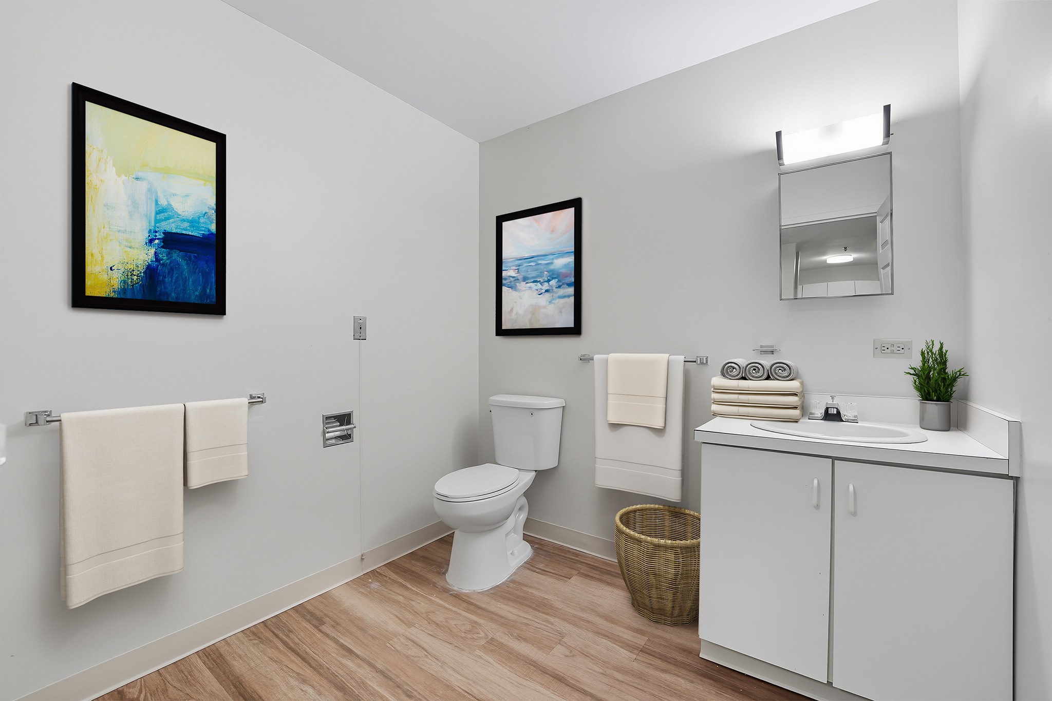 A bathroom with a toilet, sink, and two framed pictures on the wall.
