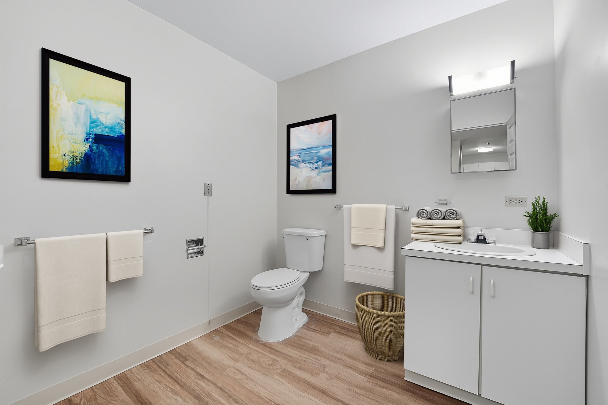 A bathroom with a toilet, sink, and two framed pictures on the wall.