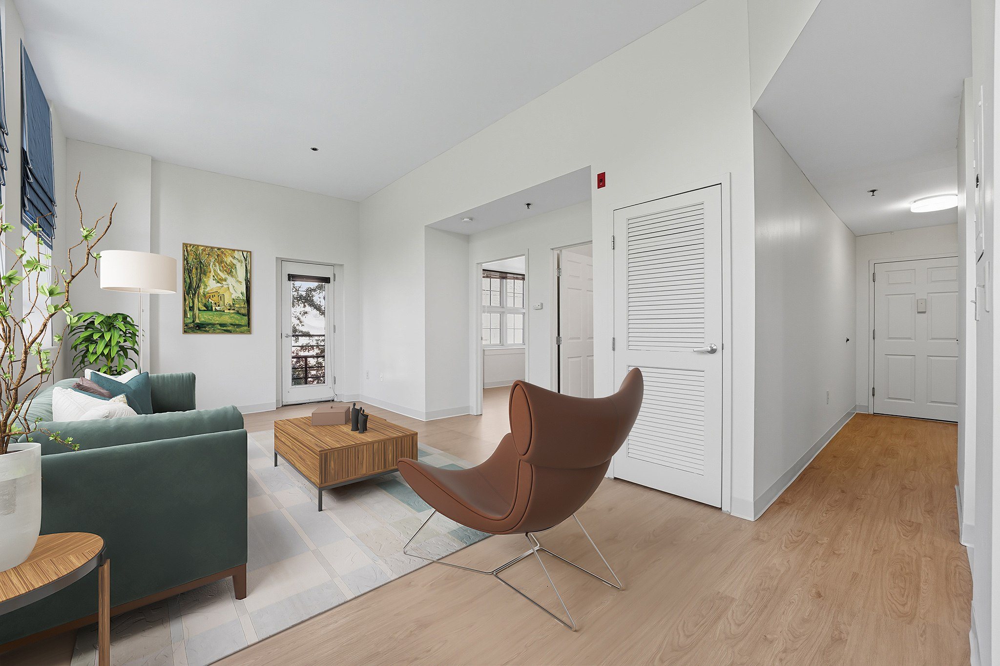 A living room with a green couch, a brown chair, and a white wall.