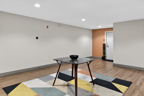 A black bowl sits on a glass table in a room with a rug on the floor.