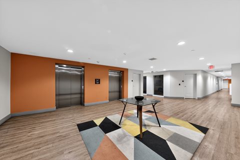 A room with orange walls and wooden floors has a table and chairs in the center.