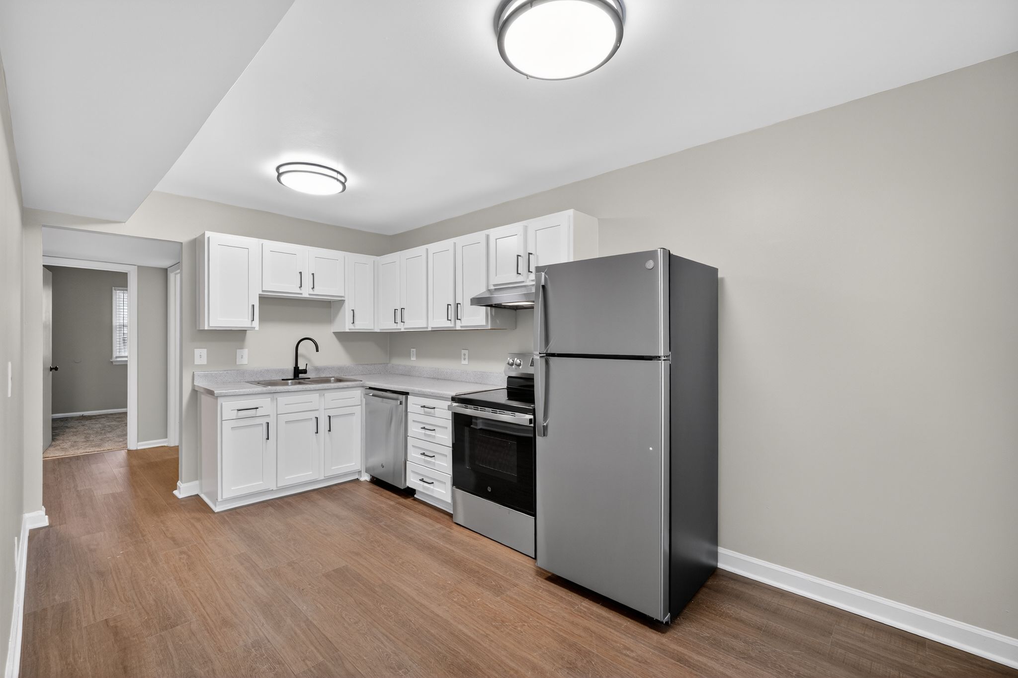 A kitchen with white cabinets and a black refrigerator.
