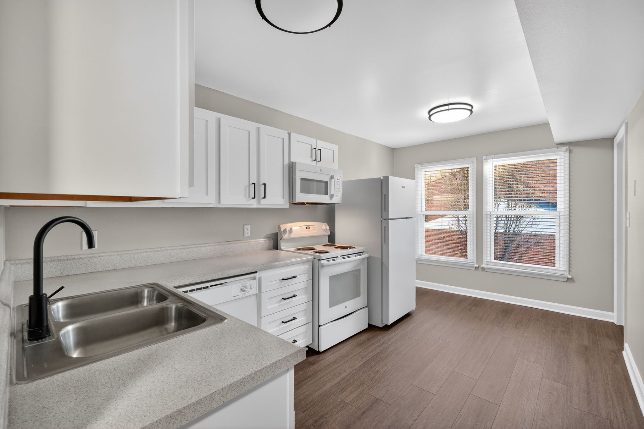 A kitchen with white cabinets and a stainless steel sink.