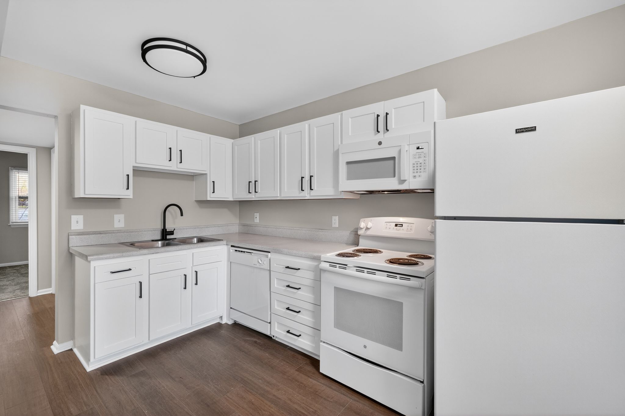 A white kitchen with a refrigerator, sink, and oven.