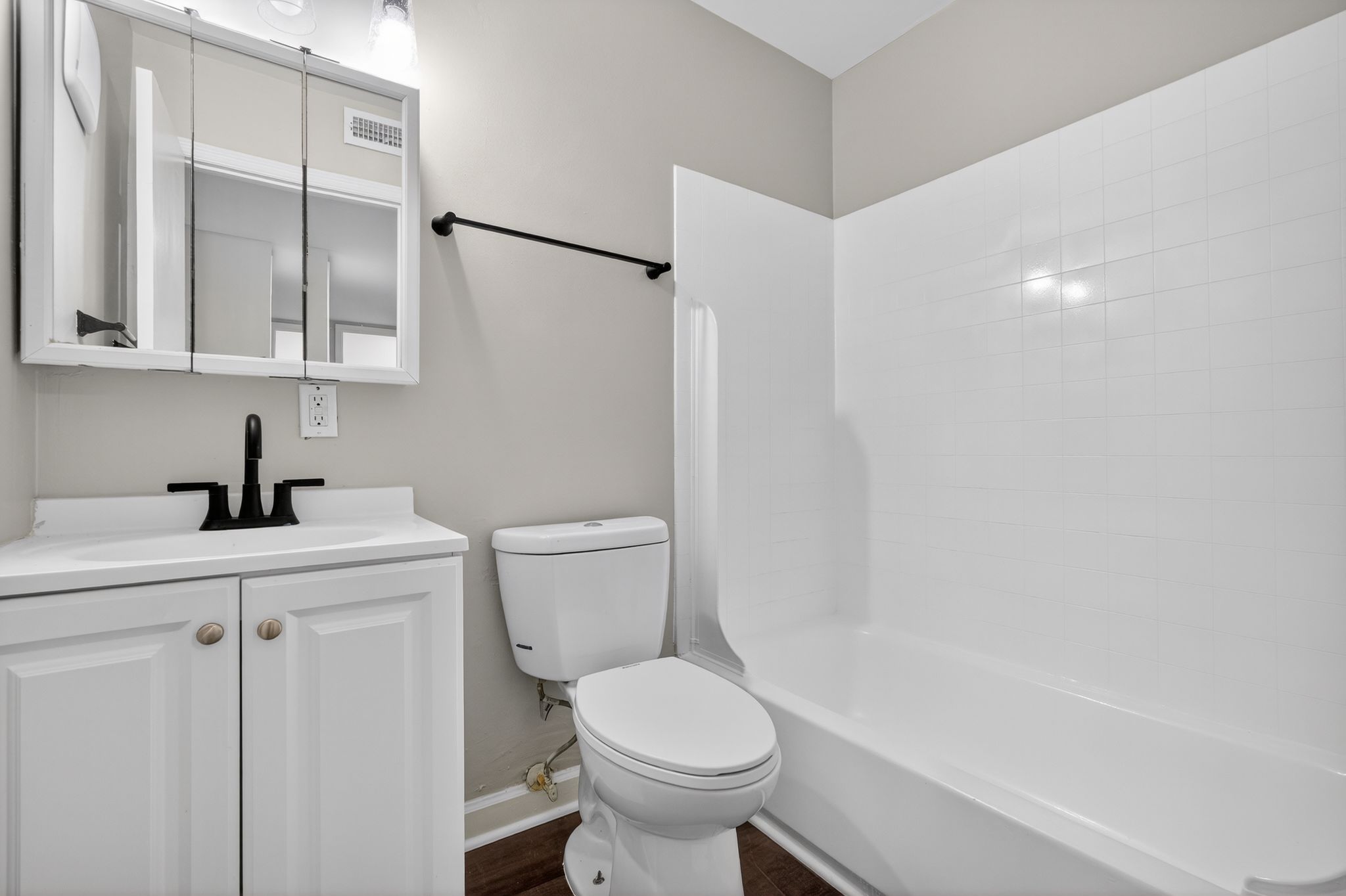A white bathroom with a toilet, sink, and bathtub.