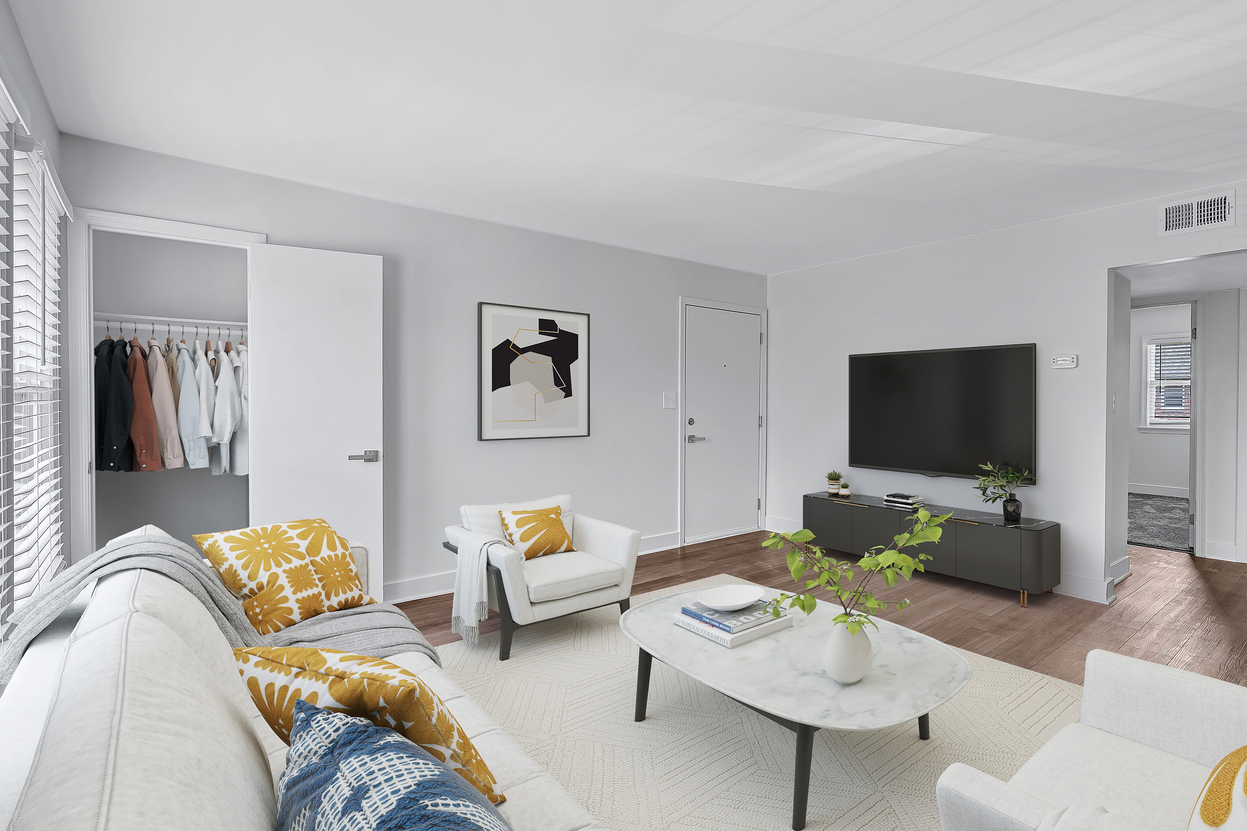 A living room with a grey couch, a white chair, a coffee table, and a television.