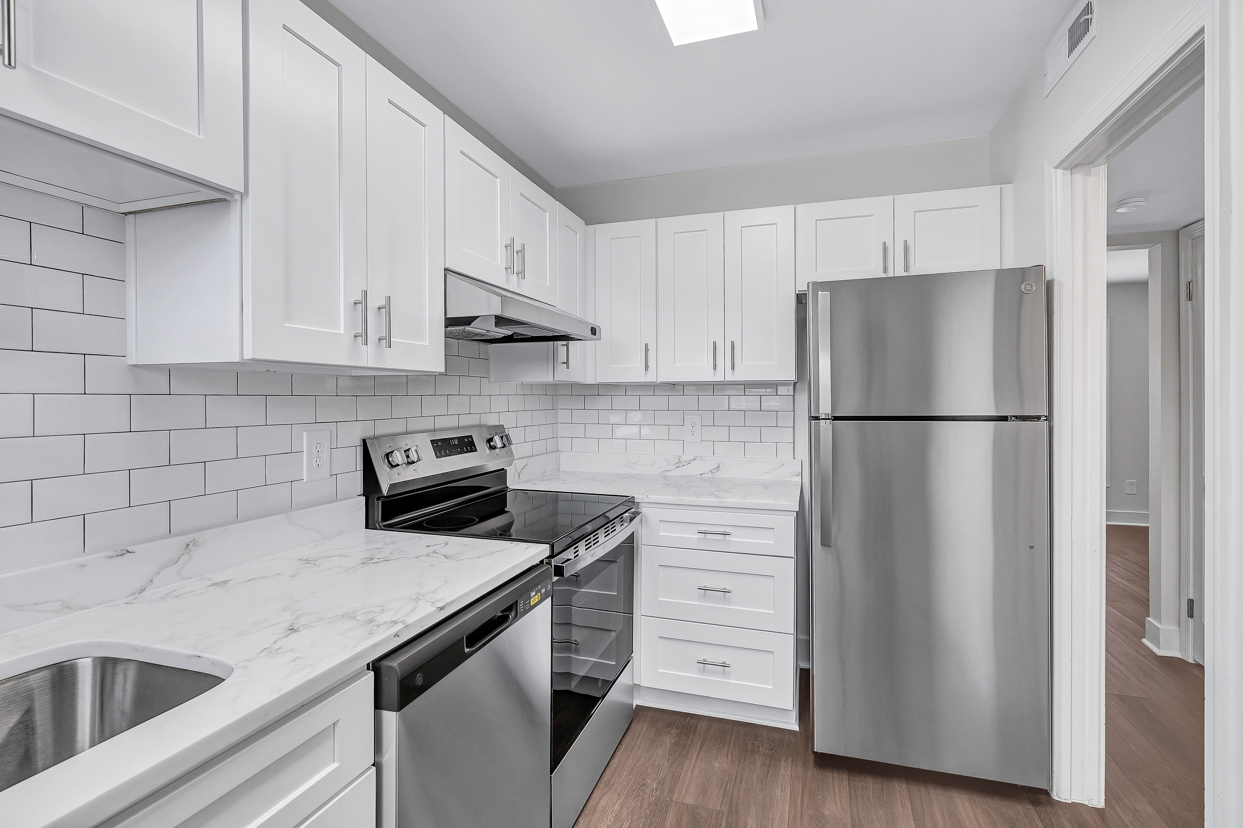 A kitchen with white cabinets and a stainless steel refrigerator.